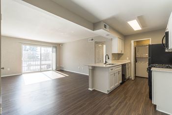 An empty kitchen and living room with a door to a balcony
